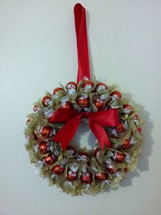 a wreath with candy wrapped in red ribbon hanging on the wall next to a white wall