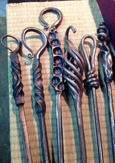 five antique metal spoons are lined up on a tableclothed place mat, with one being used as a hook