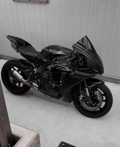 a black motorcycle is parked in front of a garage door and some bricks on the floor