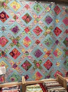 quilts are on display in a store with wooden crates holding them up against the wall