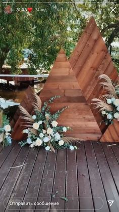 a wooden sculpture sitting on top of a wooden deck next to flowers and greenery