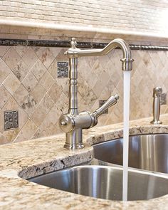 a kitchen sink with a faucet in the middle and marble counter tops above it