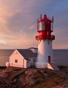 a red and white lighthouse sitting on top of a rocky cliff