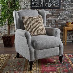 a gray recliner chair sitting on top of a rug in front of a brick wall