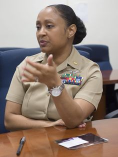 a woman in uniform sitting at a table with her hands folded out to the side