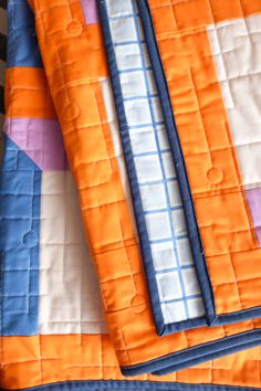 two orange and blue quilts laying on top of each other