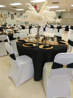 the tables are decorated with black and white linens, gold place settings, and feathers