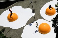 two people riding skateboards on top of giant balls in the shape of eggs and an orange ball