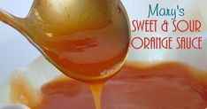 a spoon pouring orange sauce into a white bowl with the words mary's sweet & sour orange sauce