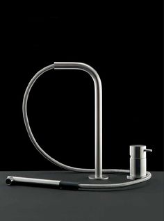 a faucet with a hose attached to it on a black surface next to a pen