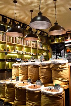 several bags of food sit in front of shelves with hanging lights above them and on the wall