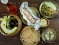 an assortment of different foods on plates with labels labeled in english and arabic letters, including fish, bread, peas, cucumbers, broccoli, lemons