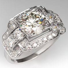 This elegant ring features a pierced design and is bordered with milgrain edging. The ring is centered with one (1) round brilliant cut diamond set into a four-prong setting. The ring is also accented with four (4), bead set, round transitional brilliant cut diamonds and thirty (30), bead set, round single cut diamonds. The ring measures 12.9mm at the top, rises 5.7mm above the finger, tapering to 1.7mm wide and 0.9mm thick at the base of the shank. The ring is currently a size 7.5. The ring is Luxury Diamond Ring For Anniversary With Classic Cut, Luxury Vintage Diamond Ring With Gemstone Details, Luxury Diamond Ring With Diamond Accents, Luxury Vintage Diamond Ring With Round Stone, Luxury Vintage Diamond Ring With Round Band, Luxury Gift Diamond Ring With Classic Cut, Vintage Luxury Ring With Round Band, Luxury Classic Diamond Ring With Brilliant Cut, Luxury Classic Rings With 17 Jewels