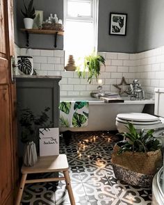 a bathroom with a toilet, tub and plants in it