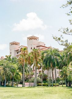 a large building surrounded by palm trees on a sunny day