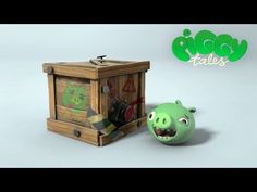 a green pig next to a wooden box with an angry face on it's side