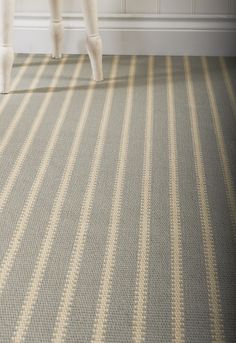 the legs of a person standing on a chair in a room with striped carpeting