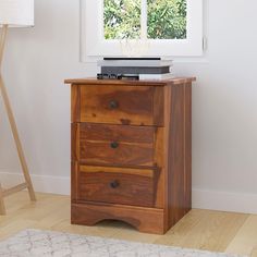 a wooden dresser with two drawers in front of a window and a rug on the floor