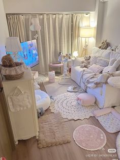 a living room filled with lots of white furniture and rugs on top of a hard wood floor