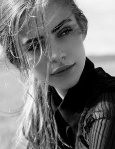 a black and white photo of a woman with her hair blowing in the wind,