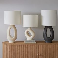 three lamps sitting on top of a wooden dresser