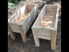 two wooden planters sitting next to each other on the ground in front of trees