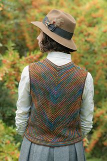 a woman wearing a hat and vest in front of some trees with orange flowers behind her