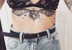 a woman with tattoos on her stomach wearing jeans