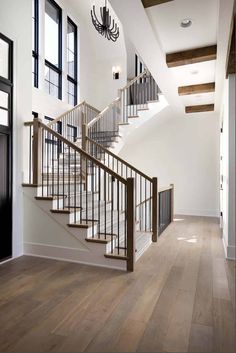 a staircase leading up to the second floor in a large white house with wood floors