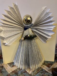 an origami book sculpture made out of old books and folded pages with a ball on top