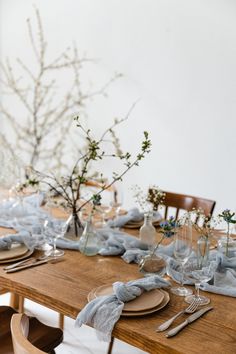 a wooden table topped with plates and place settings