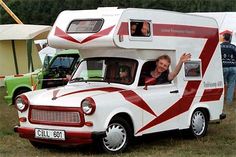 a woman waving out the window of an rv parked in a grassy area next to other vehicles