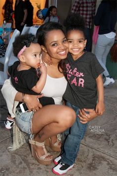 a woman holding two small children on her lap