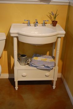 a white sink sitting next to a toilet in a bathroom under a window with yellow walls