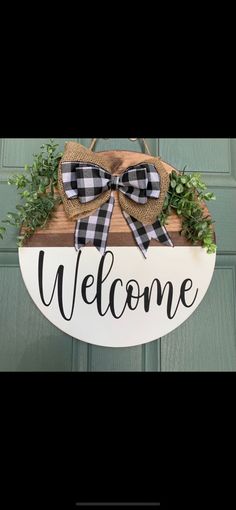 a welcome sign hanging from the front door with a bow on it's head