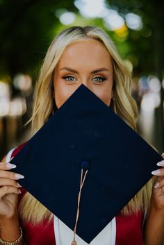 a woman wearing a graduation cap covering her face with one hand and looking at the camera