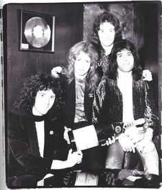 an old black and white photo of four people posing for the camera, with one holding a record