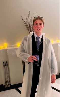 a young man dressed up in a lab coat and tie, holding a drink while posing for the camera