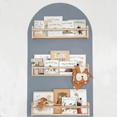 two wooden shelves with books on them in front of a blue wall