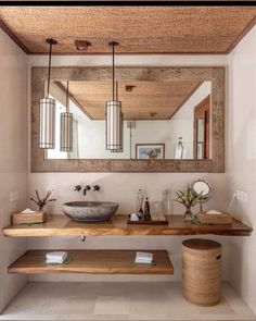 a bathroom sink sitting under a mirror next to a wooden shelf with two vases on it