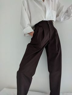 The Na Nin Townes Trousers are inspired by classic 90s style and can be worn in many ways throughout the seasons. Made with lightweight cotton, they are durable, yet allow for movement and feature a relaxed waistline that can be worn high or low on the waist. The thoughtful details of these trousers include pockets, belt loops, cuffs and double pleats. For an elegant classic look, pair with our Fiona Top in cotton poplin and your favorite gold pieces from our In House Jewelry Line. Made In USA Classic Brown Bottoms For Everyday, Classic Baggy Bottoms For Spring, Modern Cotton Bottoms For Daywear, Modern Cotton Pants For Fall, Classic Baggy Pants For Fall, Chic Baggy Bottoms For Everyday Wear, Classic Baggy Bottoms For Everyday, Chic Brown Cotton Pants, 00s Mode