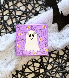 a purple and white square with a ghost on it