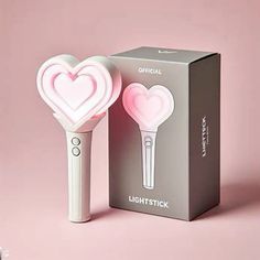 a pink lightstick shaped like a heart next to a box on a pink background