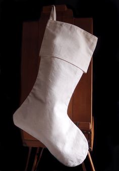 a white christmas stocking sitting on top of a wooden chair