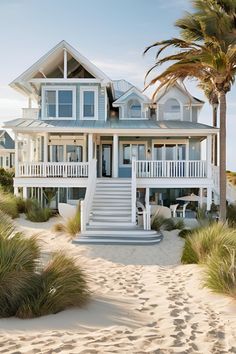 a white beach house with palm trees in the foreground and stairs leading up to it