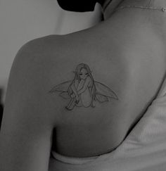 the back of a woman's shoulder with a small fairy tattoo on her left shoulder