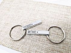 two personalized metal keychains sitting on top of a rug with the words couples written on them