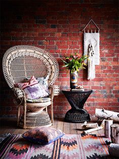 a chair and rug in front of a brick wall with a potted plant on it