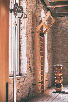 a room with brick walls and wooden flooring next to a tall rack filled with vases