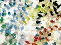 many different colored glass beads on a white surface